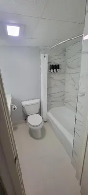 a white bathroom with a toilet and a bath tub at Royal Inn & Suites in Akron