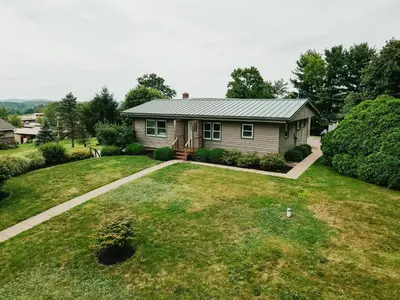 a house with a grass yard and a driveway at 3 Bedroom home outside of Berlin, Patio with Hot Tub! in Millersburg