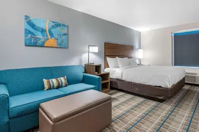 a hotel room with a bed and a blue couch at MainStay Suites Georgetown Lexington North in Georgetown