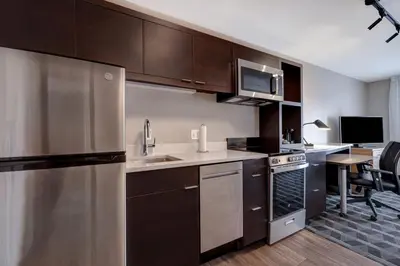 a kitchen with a stainless steel refrigerator and a table at TownePlace Suites by Marriott Monroe in Monroe
