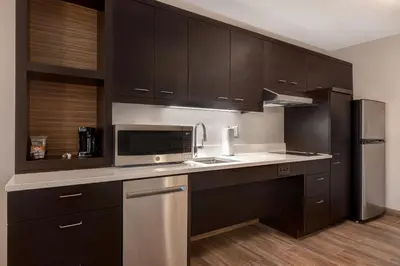 a kitchen with black cabinets and a stainless steel refrigerator at TownePlace Suites by Marriott Monroe in Monroe