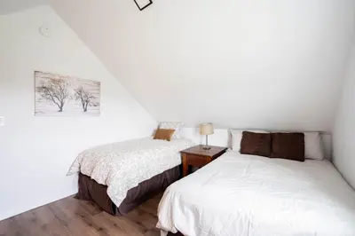 two beds in a bedroom with white walls and wood floors at Cordova Farmhouse - 7 Minutes from the Ark! in Williamstown