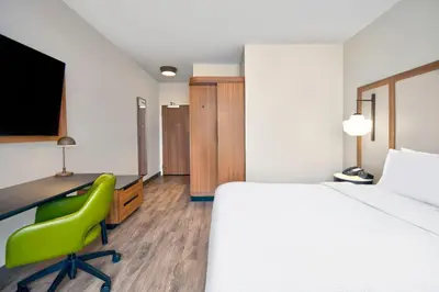 a room with a bed and a desk and a green chair at Fairfield by Marriott Inn & Suites Cincinnati North West Chester in West Chester