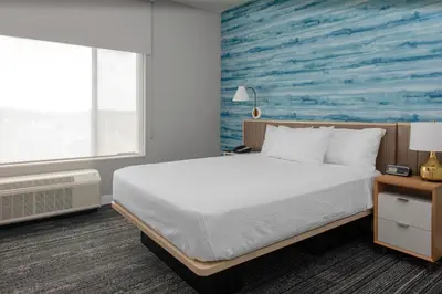 a bedroom with a bed and a blue wall at TownePlace Suites By Marriott Dayton Wilmington in Wilmington