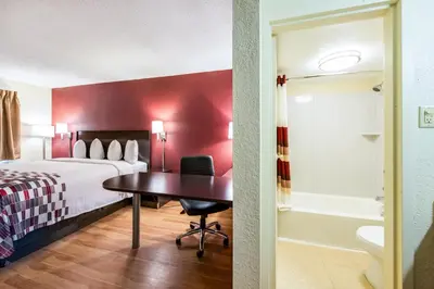 a hotel room with a bed and a desk and a bathroom at Red Roof Inn Marion, IN in Marion