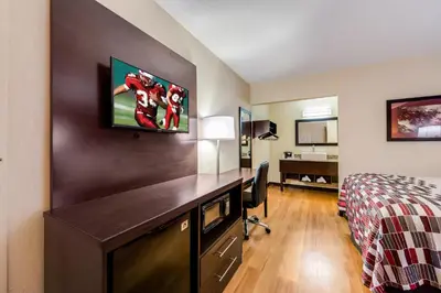 a hotel room with a desk with a television on the wall at Red Roof Inn Marion, IN in Marion