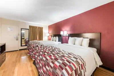 a hotel room with two beds and a red wall at Red Roof Inn Marion, IN in Marion