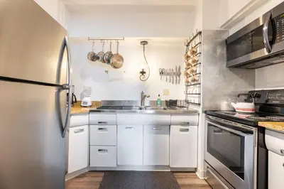a kitchen with white cabinets and a stainless steel refrigerator at Georgetown Villas 1-1b Close to Cleveland Airport and the Rocky River Valley in Fairview Park