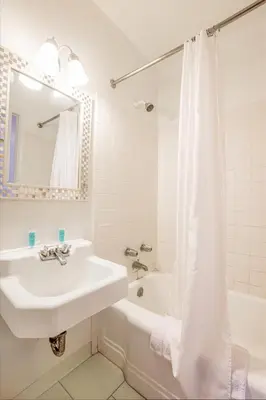 a white bathroom with a sink and a tub at Cadiz Motel by OYO on route 250 in Cadiz