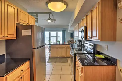 a kitchen with wooden cabinets and a stainless steel refrigerator at Resort-Style Condo with Lake-View Balcony! in Put-in-Bay