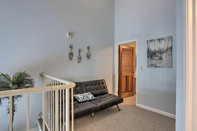 a living room with a leather couch and a staircase at Resort-Style Condo with Lake-View Balcony! in Put-in-Bay