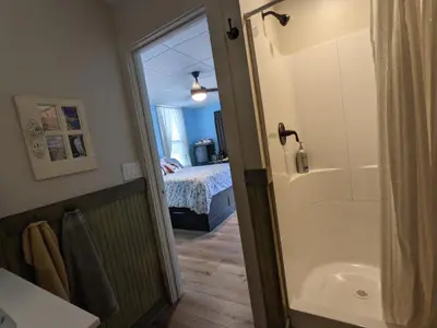 a bathroom with a shower and a tub and a bed at The Estate Studio in Downtown Milford in Milford