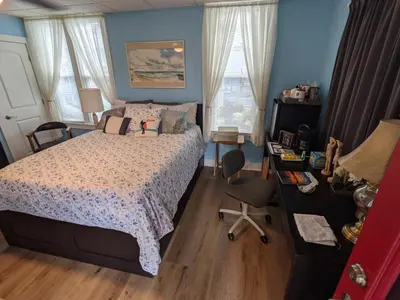 a bedroom with a bed and a desk and two windows at The Estate Studio in Downtown Milford in Milford