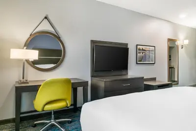 a hotel room with a bed and a desk and a yellow chair at Comfort Inn & Suites Adrian in Adrian