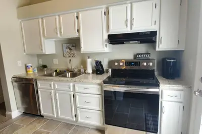 a kitchen with white cabinets and a stove and a sink at Lacinda's Cozy Home in Beckett Ridge
