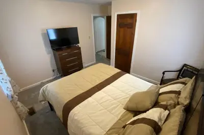 a bedroom with a bed with a dresser and a tv at Nikki's House in Cincinnati