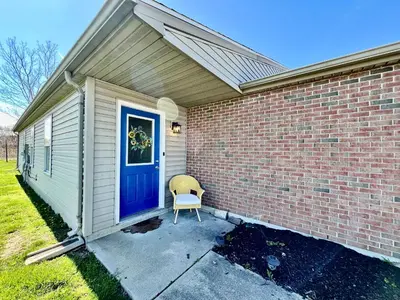 a brick house with a blue door and a chair at Lennie's House Near the Lake in Monroe
