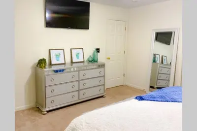a bedroom with a dresser with a television on the wall at Bailee's House in Monroe in Monroe