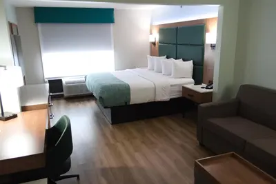 a hotel room with a large bed and a couch at Wingate by Wyndham Parkersburg-Vienna in Parkersburg
