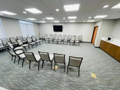 a conference room with chairs and a podium and a screen at Wingate by Wyndham Parkersburg-Vienna in Parkersburg