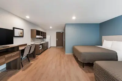 a hotel room with two beds and a desk at WoodSpring Suites Dayton North in Dayton