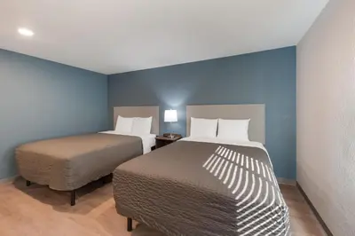 two beds in a room with blue walls at WoodSpring Suites Dayton North in Dayton
