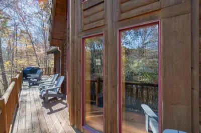a cabin balcony with chairs and a view of the woods at Creekwood Chalet - Hocking Hills with Hot Tub and Near Hiking in South Bloomingville