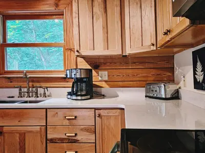 a kitchen with wooden cabinets and a counter top at Creekwood Chalet - Hocking Hills with Hot Tub and Near Hiking in South Bloomingville