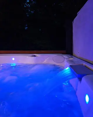 a hot tub with blue lights in the dark at Creekwood Chalet - Hocking Hills with Hot Tub and Near Hiking in South Bloomingville