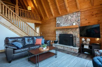 a living room with a leather couch and a fireplace at Creekwood Chalet - Hocking Hills with Hot Tub and Near Hiking in South Bloomingville