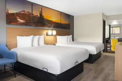 a hotel room with two beds and a blue chair at Days Inn by Wyndham Columbus Worthington in Columbus