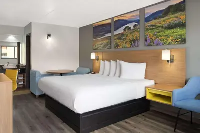 a hotel room with a bed and two chairs at Days Inn by Wyndham Columbus Worthington in Columbus