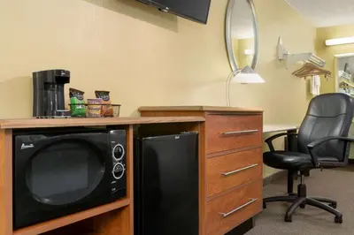 a room with a microwave and a desk with a chair at Super 8 by Wyndham Findlay in Findlay