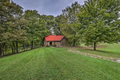 an old barn with a red roof in a field at Rustic Cabin in the Woods 2-Acre Fishing Pond! in Burlington