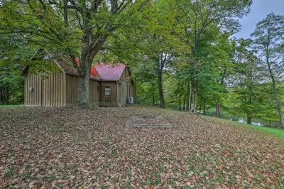 a house with a lot of leaves on the ground at Rustic Cabin in the Woods 2-Acre Fishing Pond! in Burlington