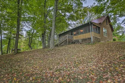 a house on top of a hill with trees at Rustic Cabin in the Woods 2-Acre Fishing Pond! in Burlington