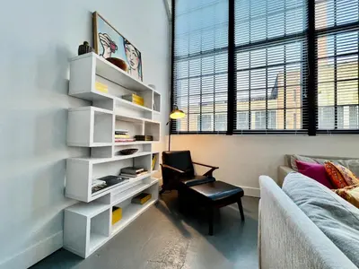 a living room with a book shelf and a chair at Swanky Loft Near Kings Island, Brewery, Bike Trail in Maineville