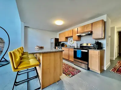 a kitchen with wooden cabinets and a yellow stool at Swanky Loft Near Kings Island, Brewery, Bike Trail in Maineville