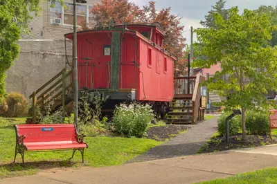 a red bench in front of a red train car at Riverfront Studio with Private Patio and Garden! in Augusta