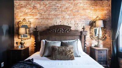 a bedroom with a large bed with a brick wall at Pickle Factory Hotel - 8BR Full Hotel with Free Parking in Covington