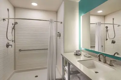 a bathroom with a shower and a sink at The Orbit Hotel, Trademark Collection by Wyndham in Fairview Park