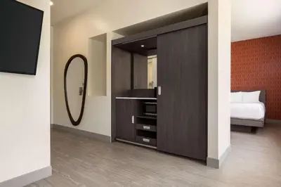 a bedroom with a large cabinet with a mirror at The Orbit Hotel, Trademark Collection by Wyndham in Fairview Park