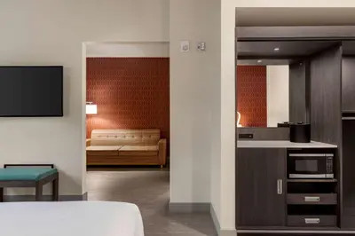 a room with a bed and a kitchen with a couch at The Orbit Hotel, Trademark Collection by Wyndham in Fairview Park
