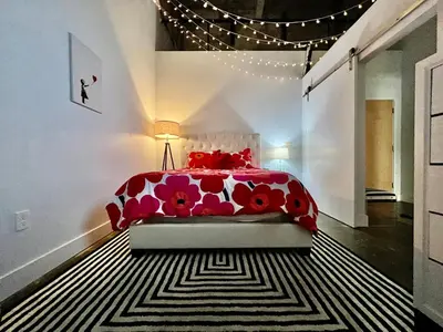 a bedroom with a red bed and a black and white rug at Kings Island Loft with Brewery, River, and Bike Trail in Maineville