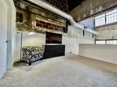 a room with a chair and a television in it at Kings Island Loft with Brewery, River, and Bike Trail in Maineville