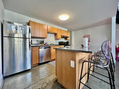 a kitchen with stainless steel appliances and wooden cabinets at Kings Island Loft with Brewery, River, and Bike Trail in Maineville