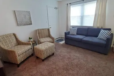 a living room with a blue couch and two chairs at Trenton's Apartment on First in Trenton