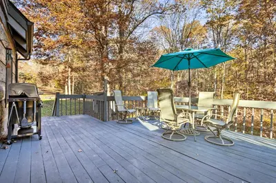 a group of chairs and an umbrella on a deck at Luxe Dog-Friendly Cabin with Hot Tub and Game Room in Logan