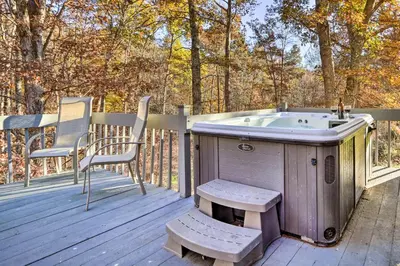 a bath tub sitting on a deck with a chair at Luxe Dog-Friendly Cabin with Hot Tub and Game Room in Logan