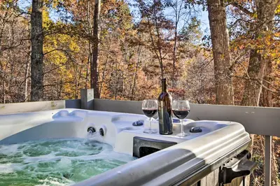 a tub with two glasses of wine and a bottle at Luxe Dog-Friendly Cabin with Hot Tub and Game Room in Logan